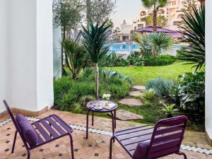 a patio with two chairs and a table and a pool at Pullman Mazagan Royal Golf & Spa in El Jadida