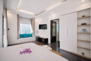 a white room with a white table with purple flowers on it at La Casa Bangtao Resort in Ban Thalat Choeng Thale