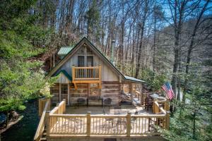 a log cabin with a deck in the woods at Creeksong Cabin in Elk Park