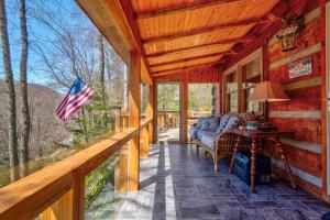 a porch of a log cabin with an american flag at Creeksong Cabin in Elk Park
