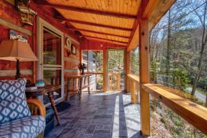 a porch of a log cabin with a couch and windows at Creeksong Cabin in Elk Park