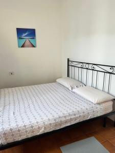 a bed with white sheets and a picture on the wall at casa rosa in Lodi