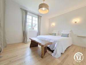 ein weißes Schlafzimmer mit einem Bett und einer Bank in der Unterkunft A Villandré in Barcugnan