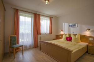 a bedroom with a large bed and a chair at Appartements Rosmarie Hollaus in Fügenberg