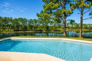 a swimming pool in front of a lake with trees at SWISS 24 - Lake Stephanie in Clermont