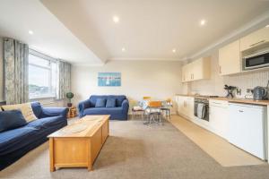 a living room with a blue couch and a kitchen at Lelola Lodge in Bournemouth