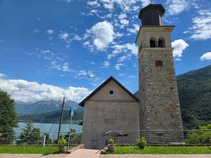 a church with a tower with a lake in the background at Olga's Paradise in Santa Croce del Lago