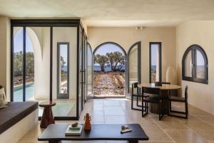 a living room with arched glass doors and a table at Exomitis1 Cellar & Sea Escape in Agios Georgios Thalassiti