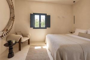 a bedroom with a bed and a chair and a window at Exomitis1 Cellar & Sea Escape in Agios Georgios Thalassiti +36 photos