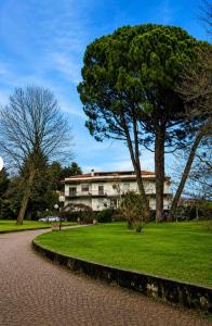 a building in a park with a tree and grass at Relais Lungolago Gavirate in Gavirate
