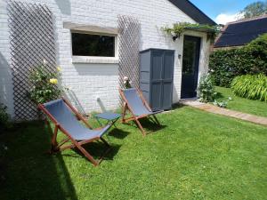 two chairs sitting in the grass next to a house at Le Pavillon in Céroux-Mousty