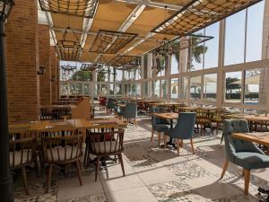 a restaurant with wooden tables and chairs and windows at Mercure Ismailia Forsan Island in Ismailia