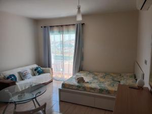a bedroom with a bed and a couch and a glass table at Seaview Holiday Studio Peyia in Peyia
