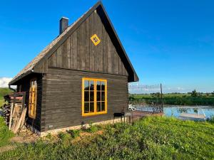 a small wooden building with a yellow window on it at Sunset sauna Bauska in Jumprava