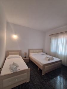 two twin beds in a room with a window at Old Village Apartment in Dhërmi