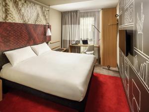 a hotel room with a large white bed and a desk at ibis Glasgow City Centre – Sauchiehall St in Glasgow