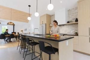 a woman standing at a counter in a kitchen at Spa & Babyfoot - Chalet BOREA in Saint-Faustin