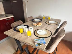 a wooden table with plates of food and glasses of orange juice at Cozy apartment Ivana in Gornji Karin