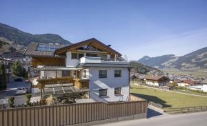 a white house with a wooden fence and mountains at Haus Gondelspaß in Fügen