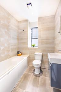 a bathroom with a toilet and a tub and a sink at Modern City Centre Flat in Norwich