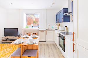 a kitchen with white cabinets and a wooden table at Modern City Centre Flat in Norwich