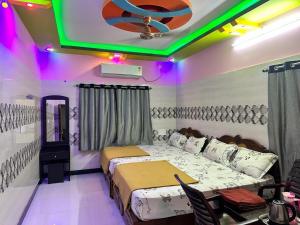 a bedroom with two beds and a green lighting at GTR Royal Palace cottage in Wodapatti +2 photos