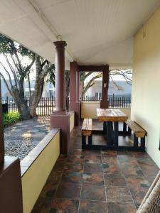 a porch with benches and a table and a tree at The Museum in Sabie