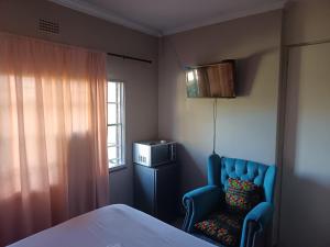 a bedroom with a bed and a chair and a window at Fourways guesthouse & spa in Fourways +2 photos