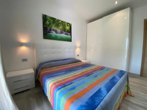 a bedroom with a bed with a colorful striped blanket at R House II - Puntocasabudoni in Budoni