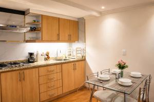 a kitchen with wooden cabinets and a table with chairs at Comfortable with Private Garage and Excellent Location Rb in Riobamba
