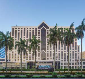 a large building with palm trees in front of it at ARTOTEL Gelora Senayan Jakarta in Jakarta