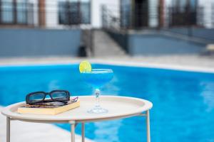 a drink on a table next to a swimming pool at In Gremi Hotel in Gremi
