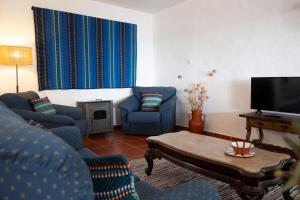 a living room with blue chairs and a tv at Dom Nuno by Horta da Moura in Monsaraz +34 photos