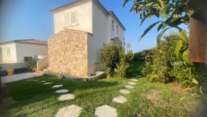 a house with a grass yard with a building at R House II - Puntocasabudoni in Budoni