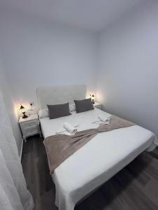 a bedroom with a large white bed with two pillows at Apartamento Empul Barrosa Beach in Novo Sancti Petri