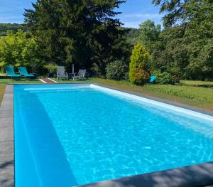 a blue swimming pool with chairs in a yard at La Fraizière in Arnaville