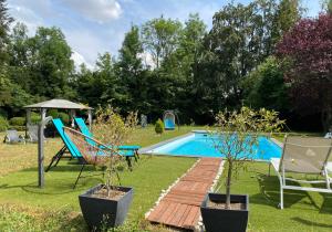 a yard with a swimming pool with two chairs and an umbrella at La Fraizière in Arnaville