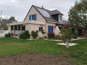 a white house with blue windows and a yard at maison fleurie in Longué