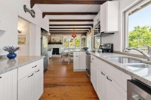 a kitchen with white cabinets and a large window at Walk to Oceanside Beach in Wellfleet