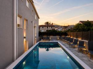 a swimming pool with chairs next to a building at Villa Dante with swimming pool in Trogir