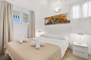 two beds in a bedroom with white walls and windows at 4Brothers by 3VILLAS in Cala en Porter