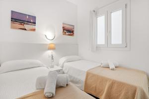 a white room with two beds and a window at 4Brothers by 3VILLAS in Cala en Porter