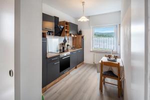 a kitchen with black cabinets and a table and a window at Fewo zum Eisenstollen in Balve