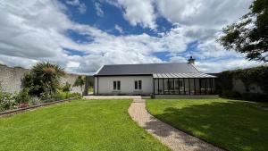 a large white house with a grass yard at Garden Cottage on Tintern Trails in Fethard on Sea
