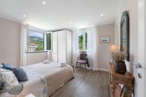 a bedroom with a bed and a chair and windows at Casa Due Ulivi in Lavagna
