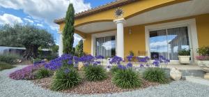 a yellow house with purple flowers in a yard at Une Belle Histoire in Argelliers