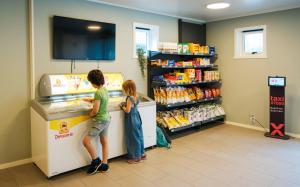 two children standing at a cash register in a store at Topcamp Mosjøen - Helgeland in Mosjøen