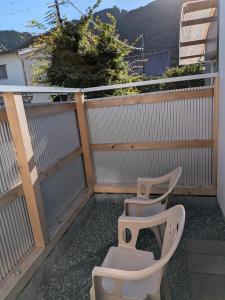 a balcony with two white chairs and a fence at Kumanokodo KURA in Shingū
