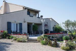 a white house with red flowers in a yard at chambre d'hotes les cigales in Comps