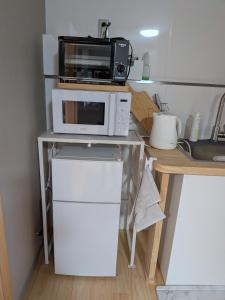 a kitchen with a microwave and a refrigerator at Kumanokodo KURA in Shingū +4 photos